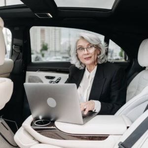 older female executive with laptop in the back of a car