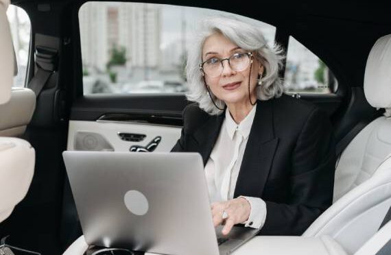 older female executive with laptop in the back of a car