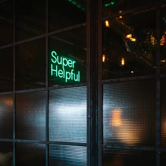 Be super helpful! You will be rewarded. A sign saying Super Helpful at night.