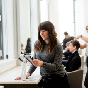 woman in gray sweater holding tablet computer
