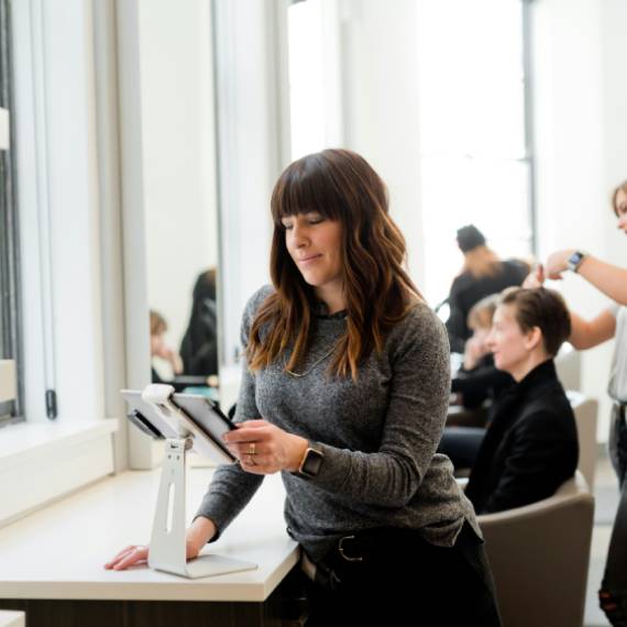 woman in gray sweater holding tablet computer