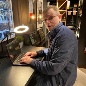Warren Laine-Naida working on his laptop, looking at the camera
