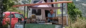 unsplash image. a man in France sells olive oil from a trailer at the side of the road.