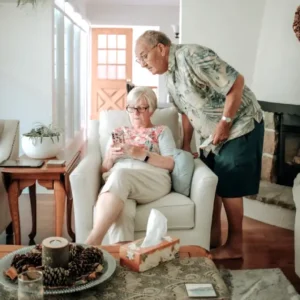 an elderly man and woman looking at a smartphone in their living room