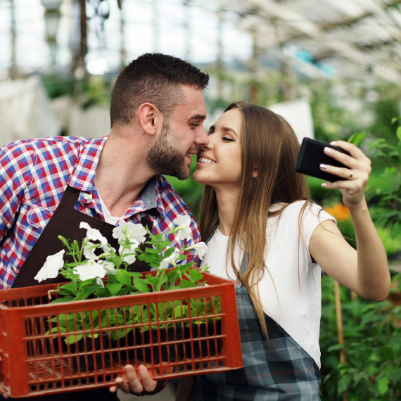 a couple in a greenhouse taking a selfie