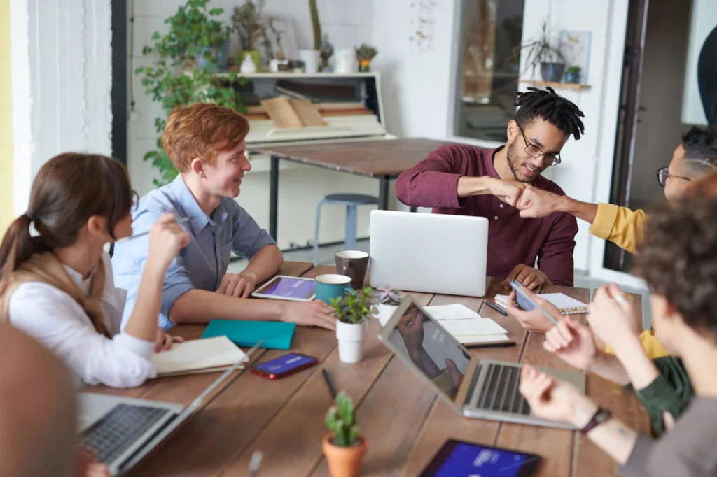 happy workers at an office table with laptops