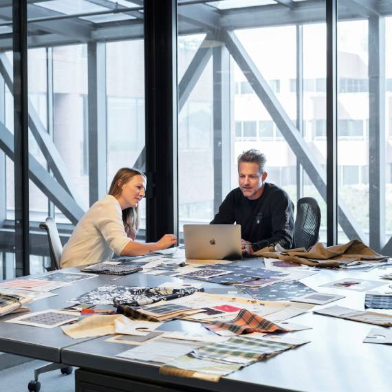 man and woman in office at conference table working on a laptop